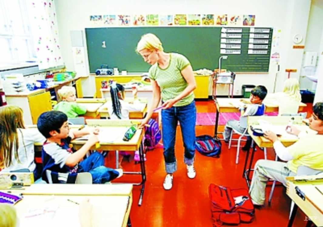 教室里，女教师在课桌间走动查看，学生们坐在座位上学习。 · 图片来源：www.xinhuanet.com