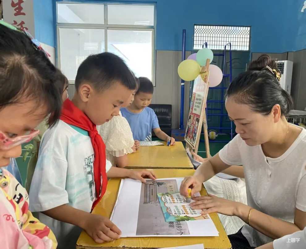 教师为学生的闯关卡盖章，孩子们围桌参与 · 图片来源：www.jjxw.cn