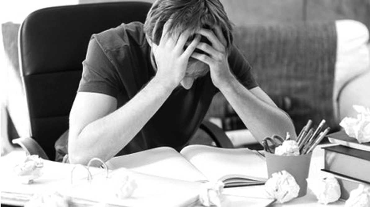 学生双手抱头伏在摊开的书本前 · 图片来源：qnck.cyol.com
